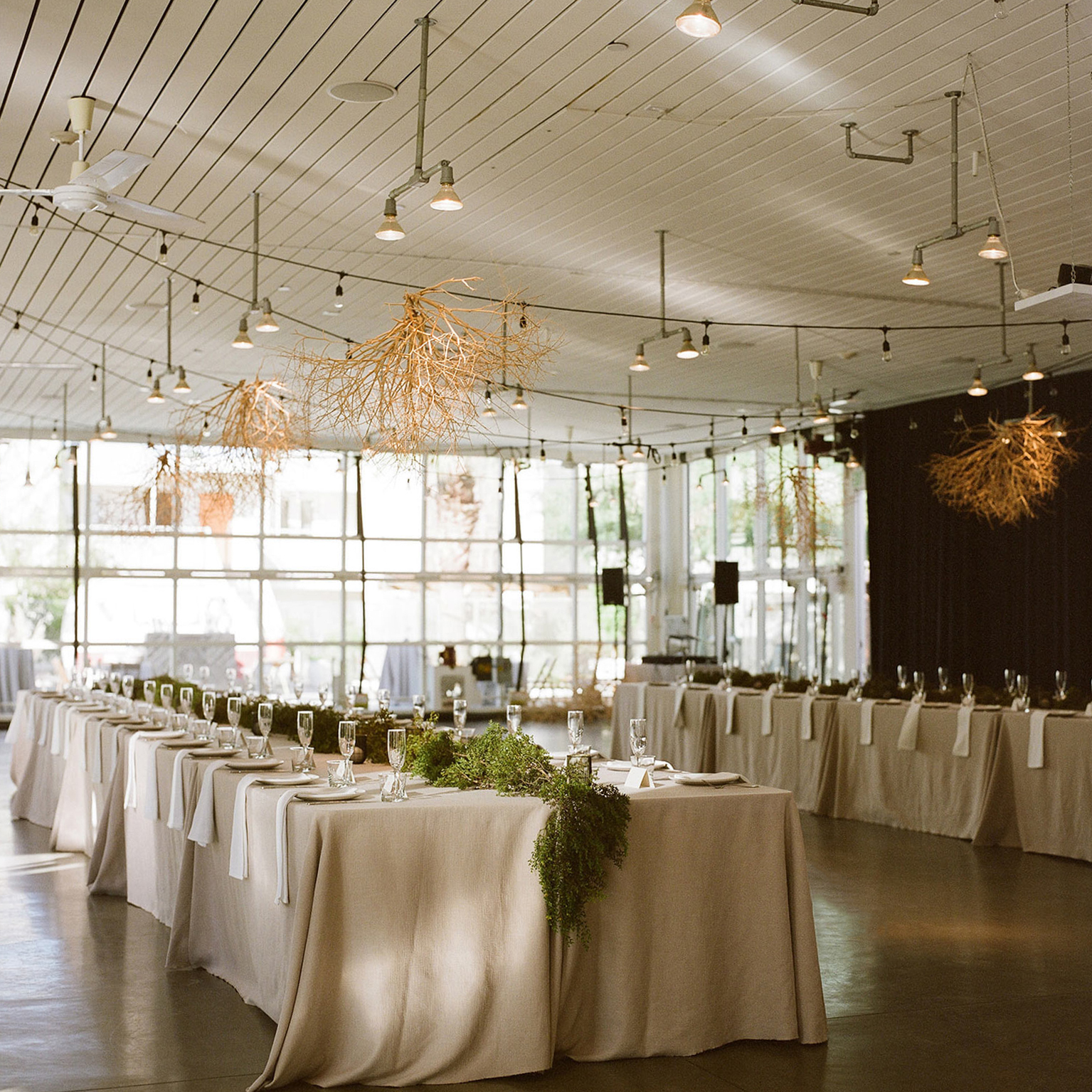 Extra wide shot of one of the long tables for guests where tumbleweeds collected for decoration over the tables with care. The tablecloths are a floor-length in natural flax linen with creosote garlands running down the center. 