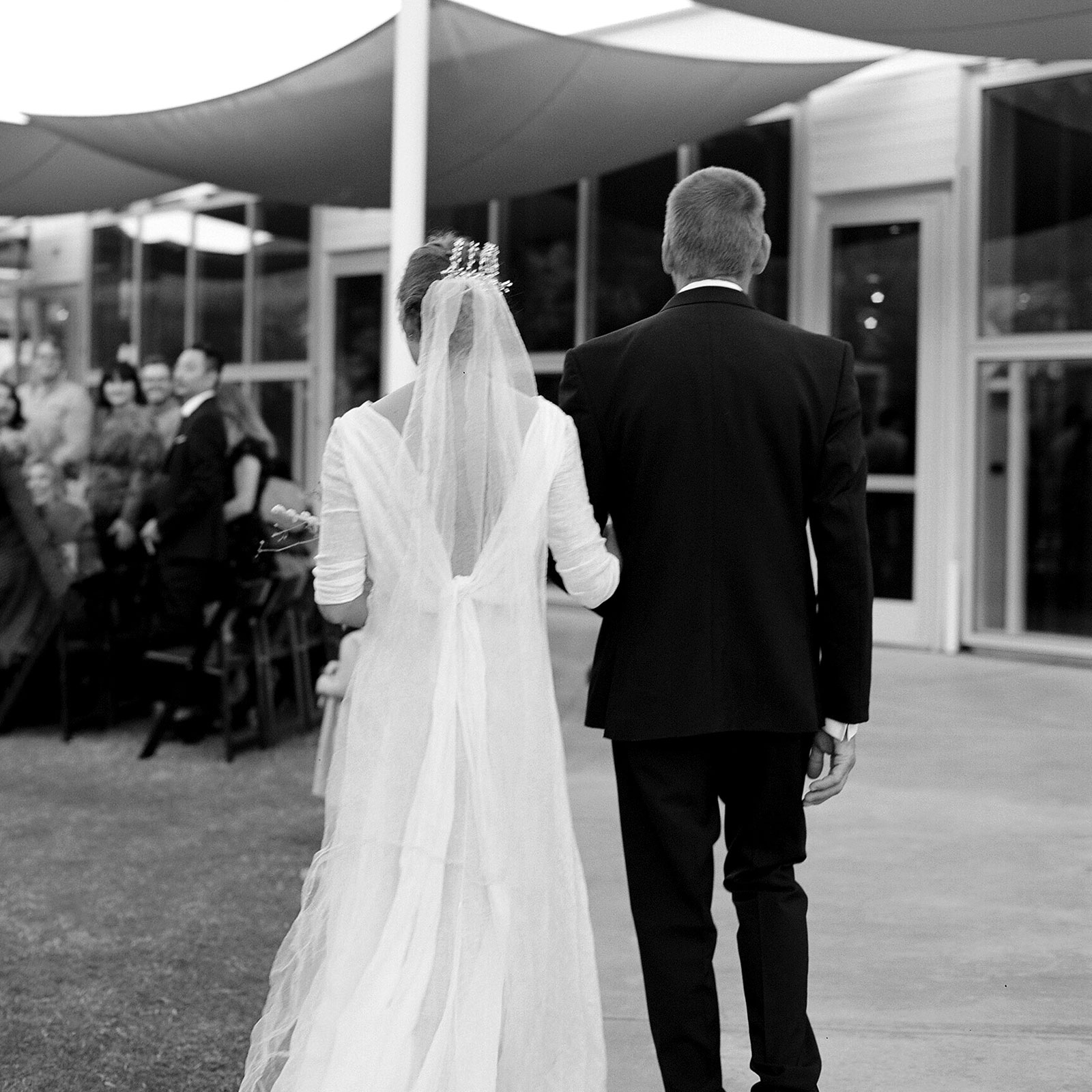 Black and white medium shot of K and her father as they walk down the aisle. 