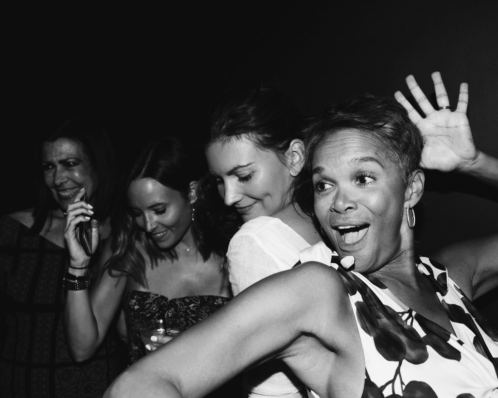 Black and white candid of party guests dancing with K.