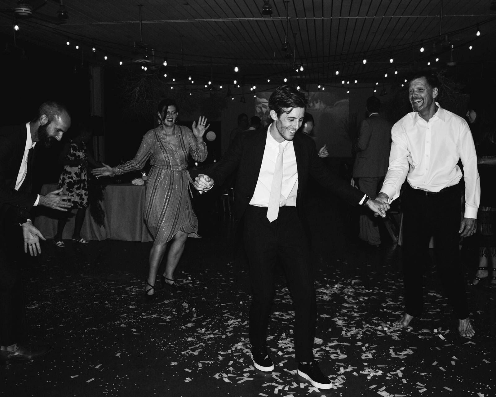 Black and white candid of E dancing with white paper confetti all over the ground.