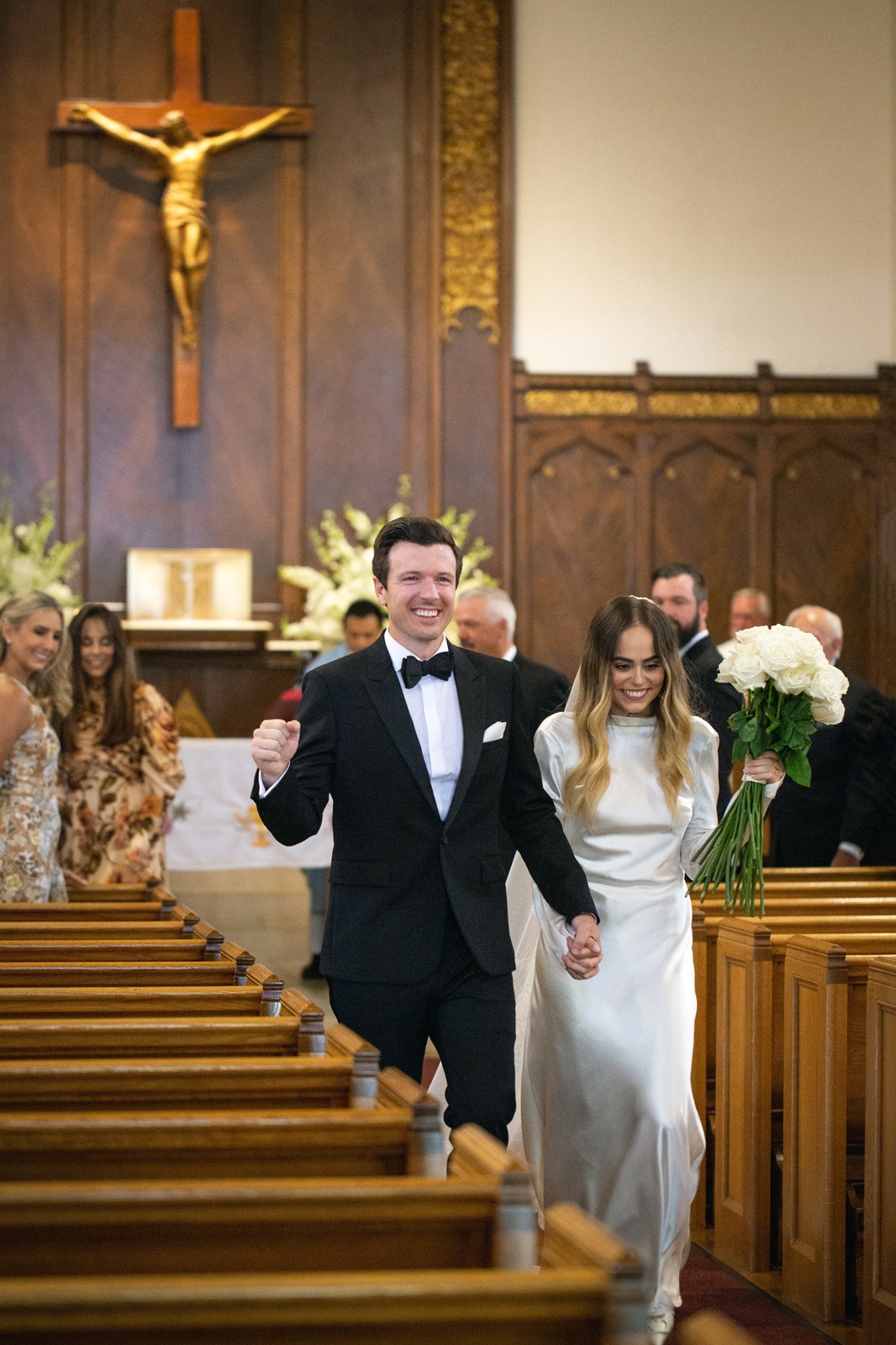 Wide shot of M and C walking down the aisle towards the camera.