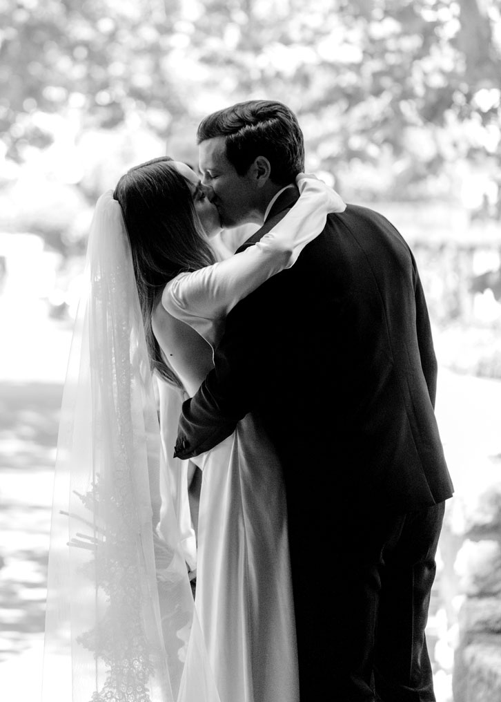 Black and white medium shot of M and C kissing from the perspective of the camera in the church looking outside. The couple is slightly in silhouette.