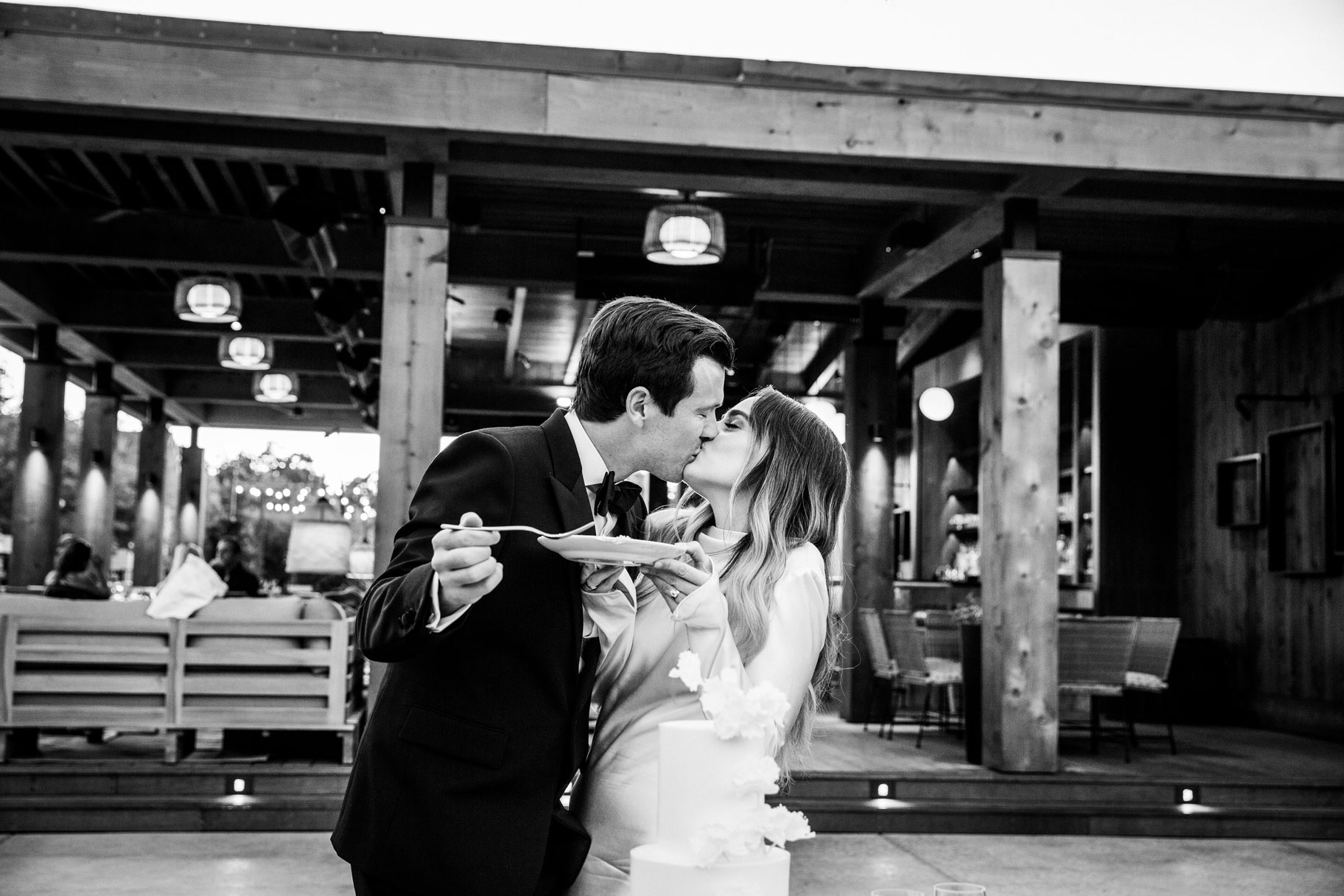 Black and white shot of the couple eating a piece of cake together.