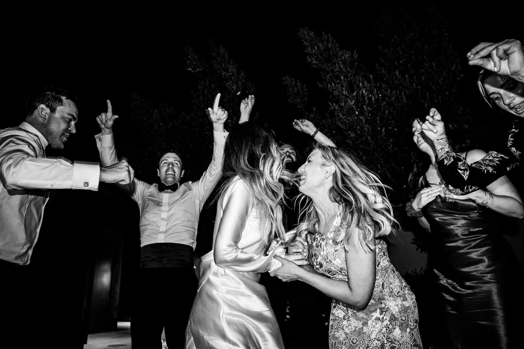 Black and white candid shot of the bride and her new sister in law dancing together in joy.