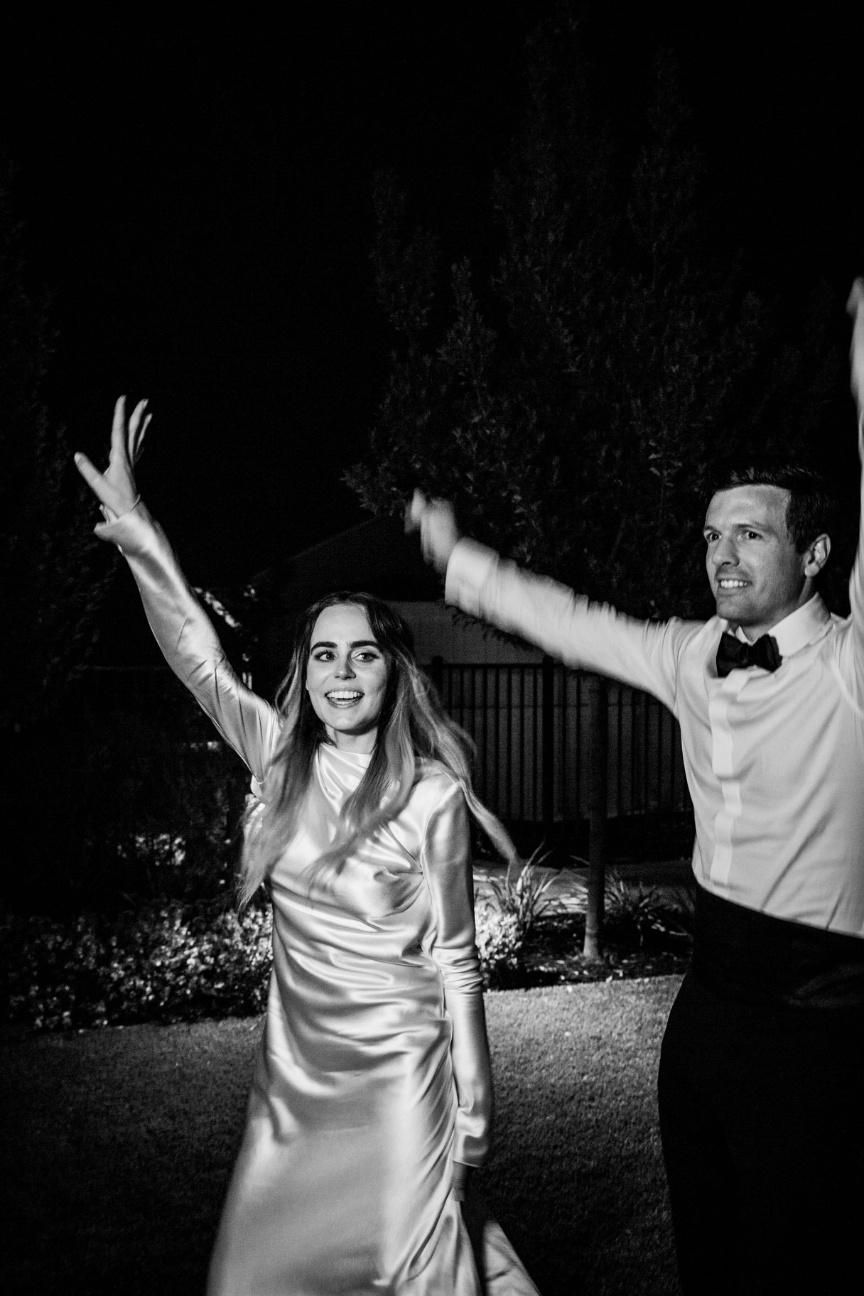 Black and white candid shot of the couple dancing the night away smiling towards the camera.