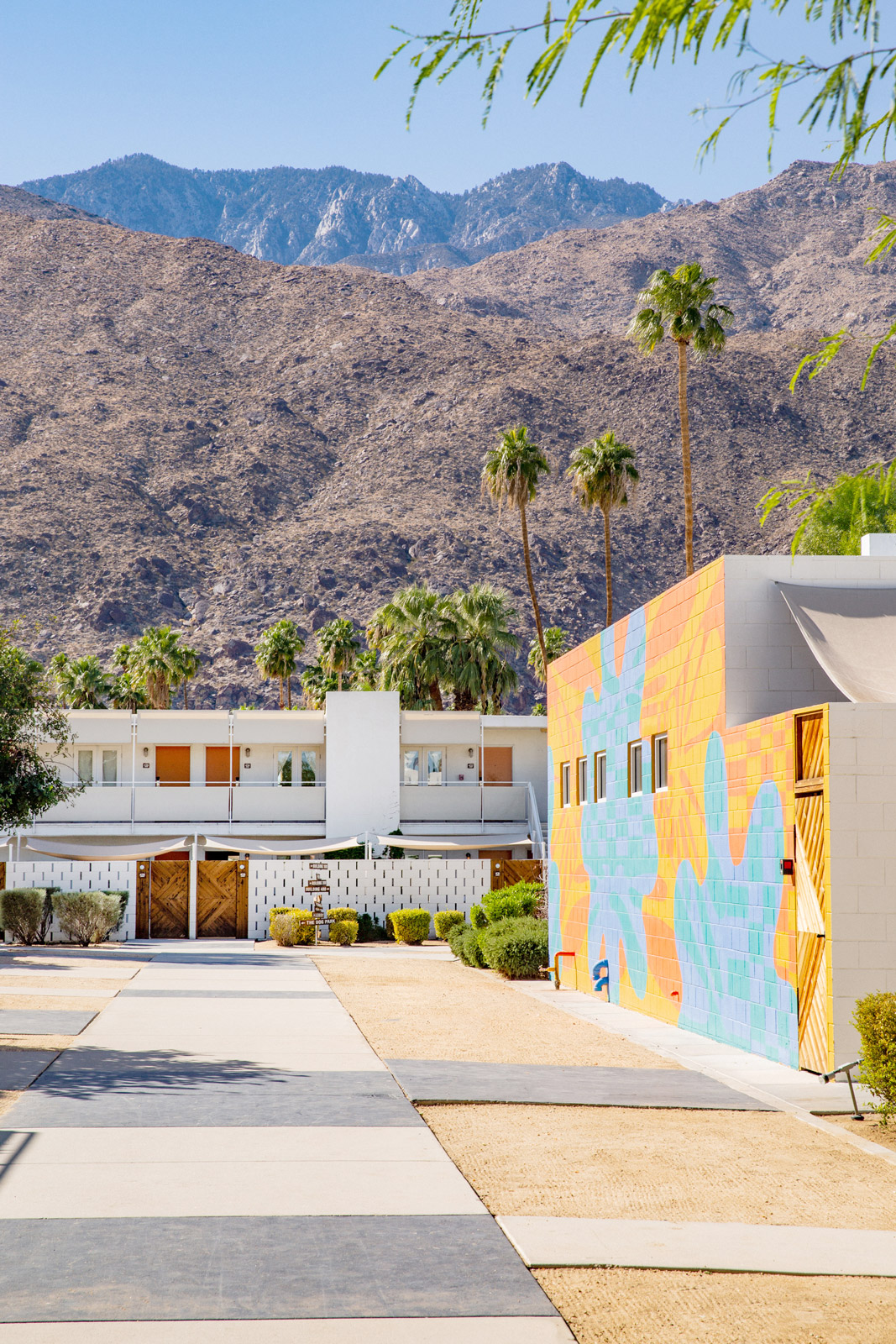 Inside Ace Hotel grounds in sunny October depicting the main walkway with famous mural. Looking past the ace grounds and up into the picturesque San Jacintos mountains.