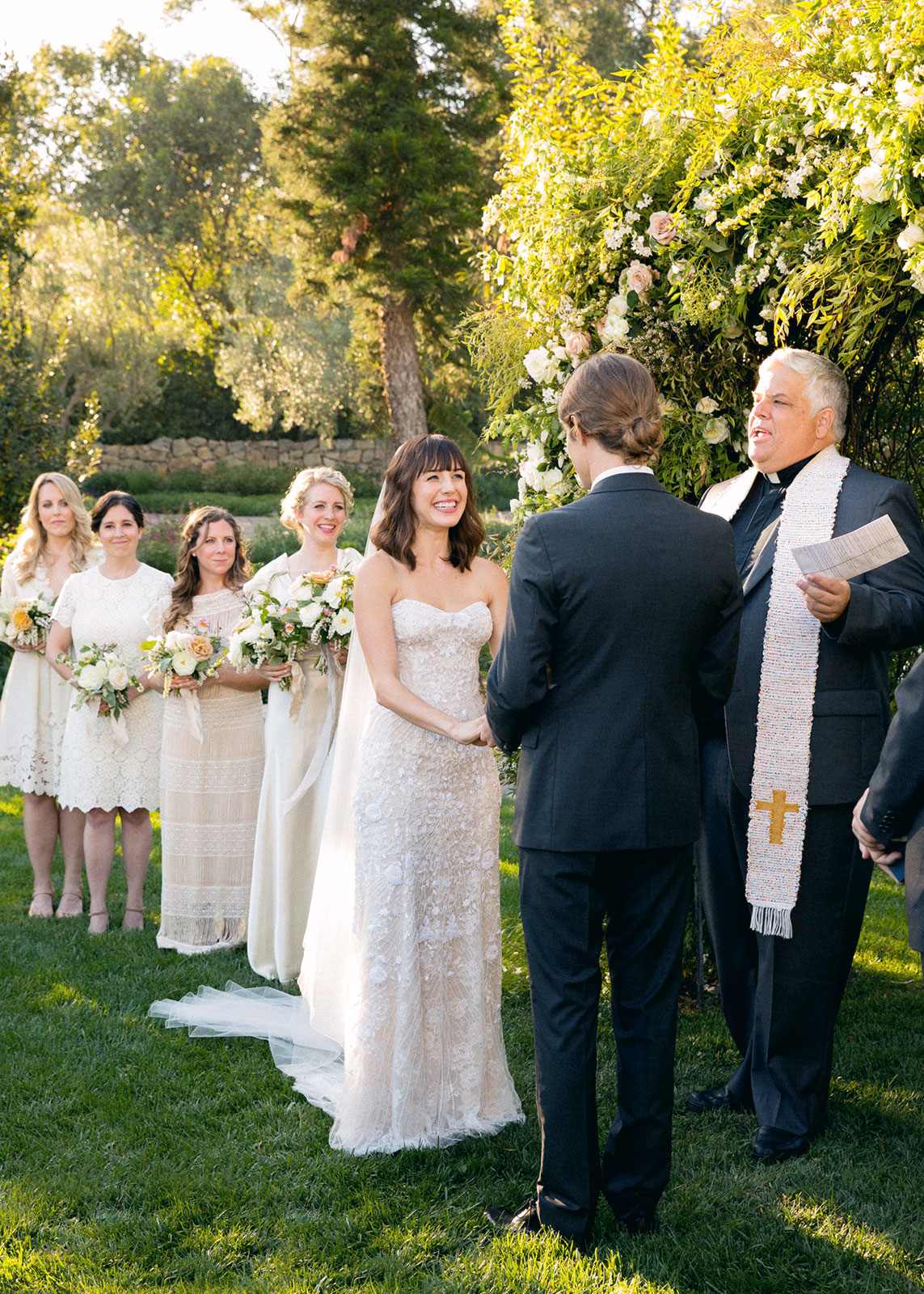 Wide shot of the bride smiling at the groom with her maidens behind her.