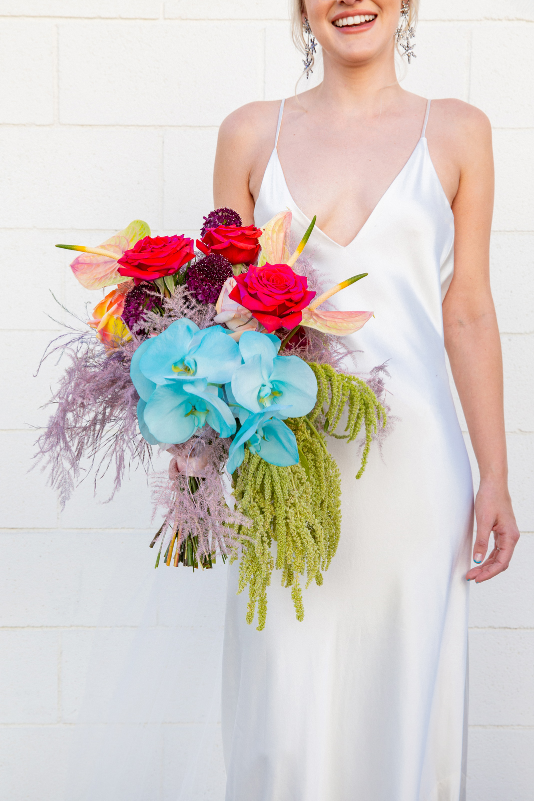 Medium shot of K holding her bridal bouquet designed by Wheelhouse Design & Florals. The bouquet featured large blooms that created big pops of colors like bright red, moody burgundy, pale pink, sage green and turquoise.