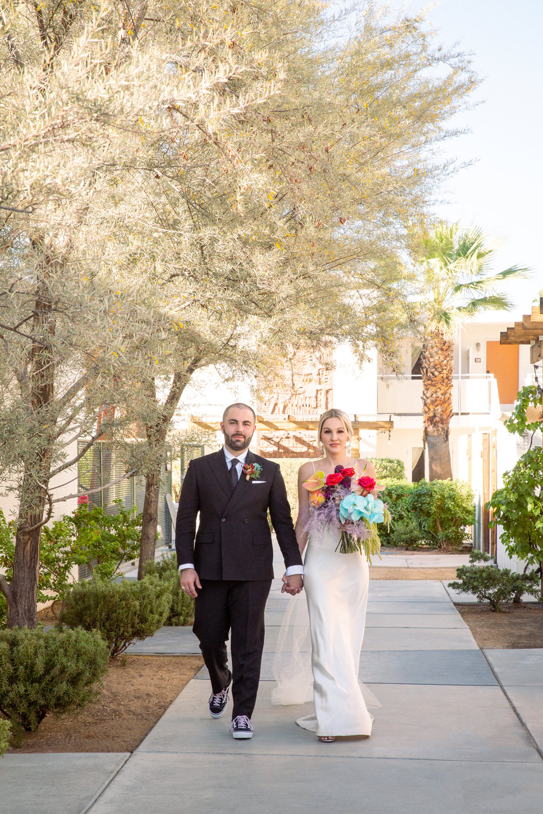 Wide shot of K and B holding hands while walking toward the camera.