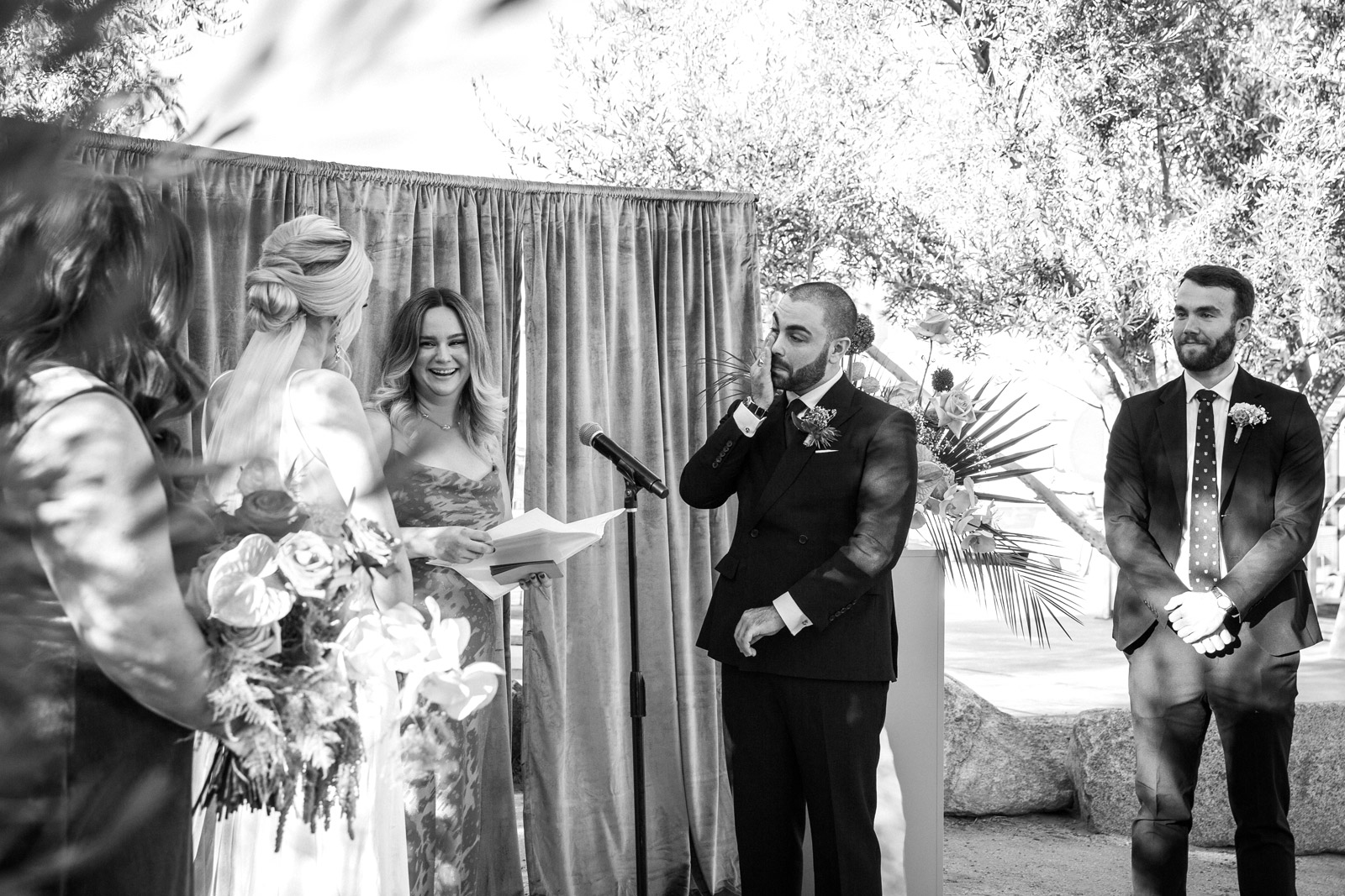 Wide shot of the scene. B wipes tears from his face as the oficiant smiles. Here is a quote from K herself "We wrote our own vows. Embarrassingly, we both wrote them pretty last minute but they were so special. We even shared some of the same sentiments like being each other’s sounding-board.”