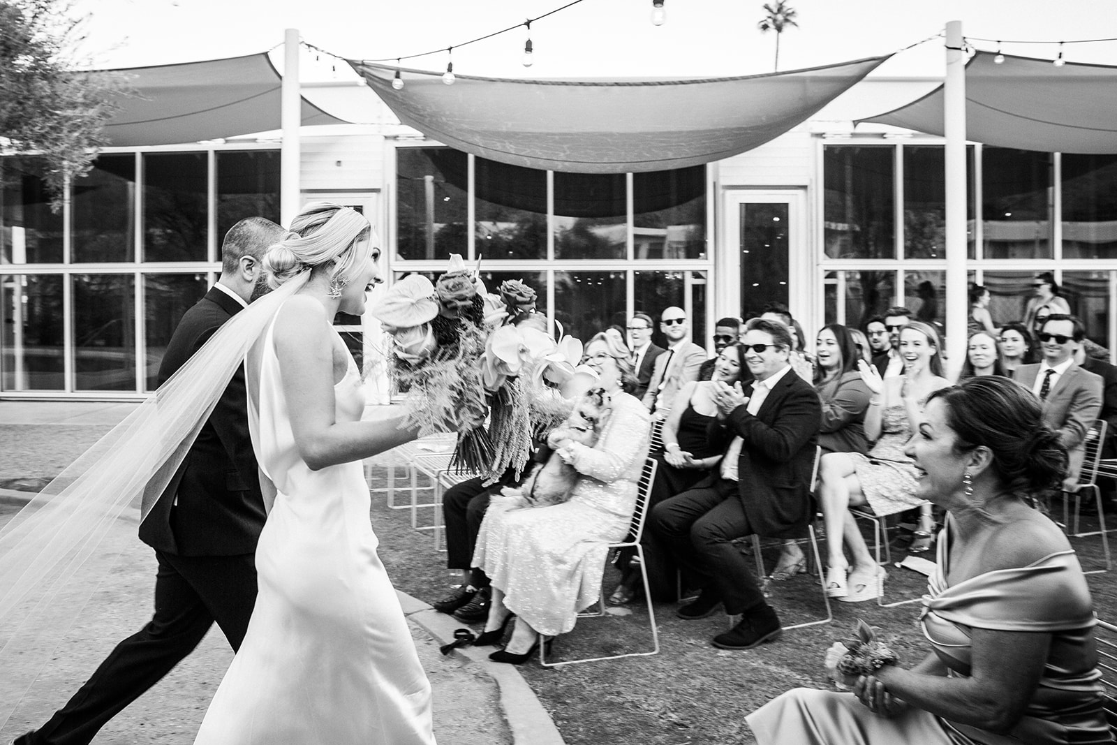 Medium shot of K and B walking away from camera as they make their way down the aisle for the first time as a single unit.