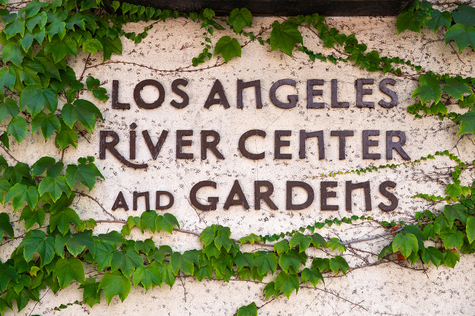 Close-up shot of the Los Angeles River Center and Gardens sign outside the entrance. It appears to be overgrown by an Ivy vine.