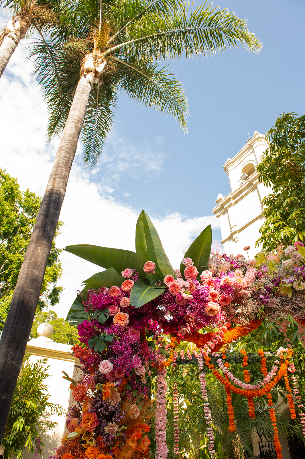 Another close-up detail shots of A and H’s wedding mandap with the blue sky and white bell tower in the distance.