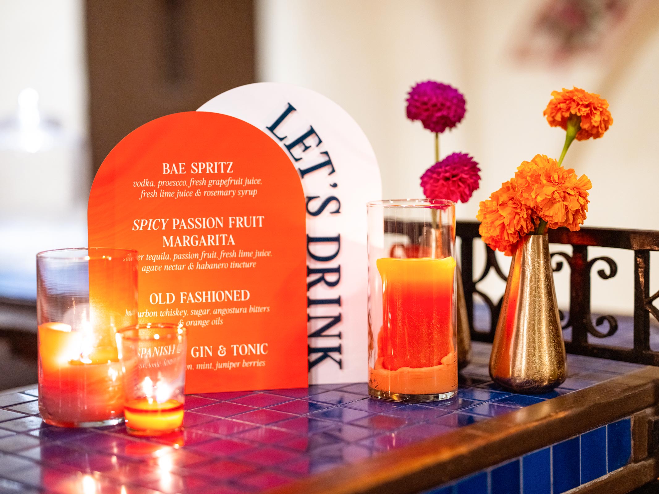 Close-up shoot of a bar with a centerpiece that is a bright orange and white curved menu with the bold heading "LET