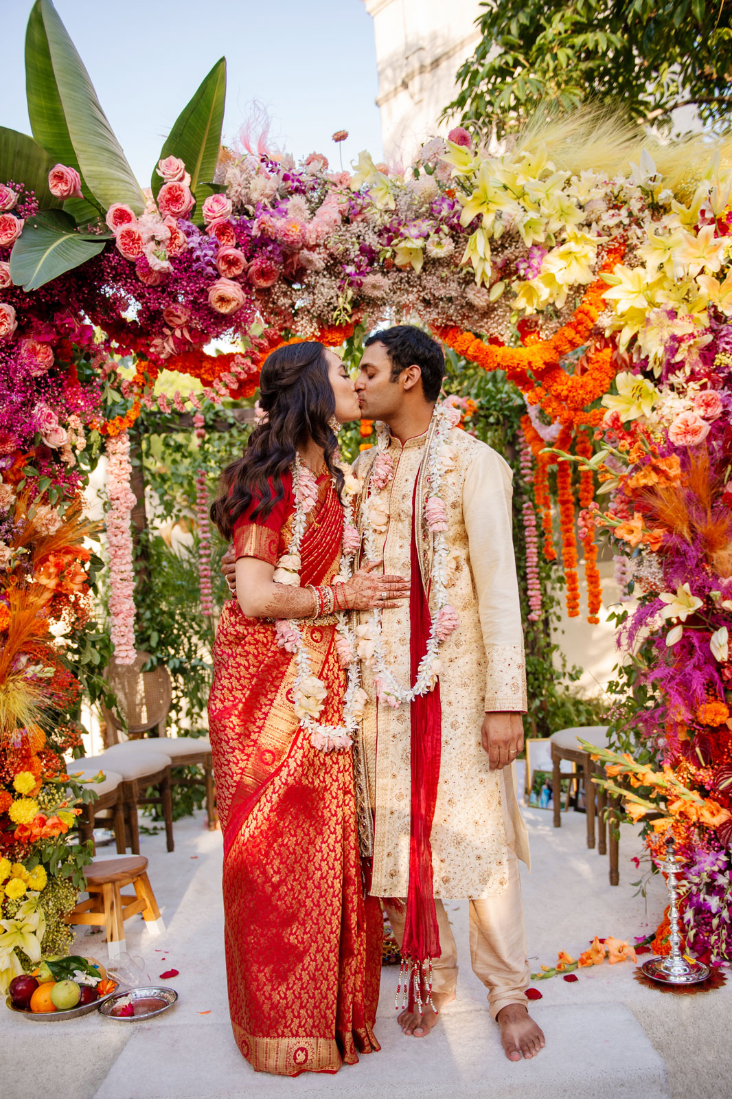 Full body portrait of A and H under the mandap kissing.